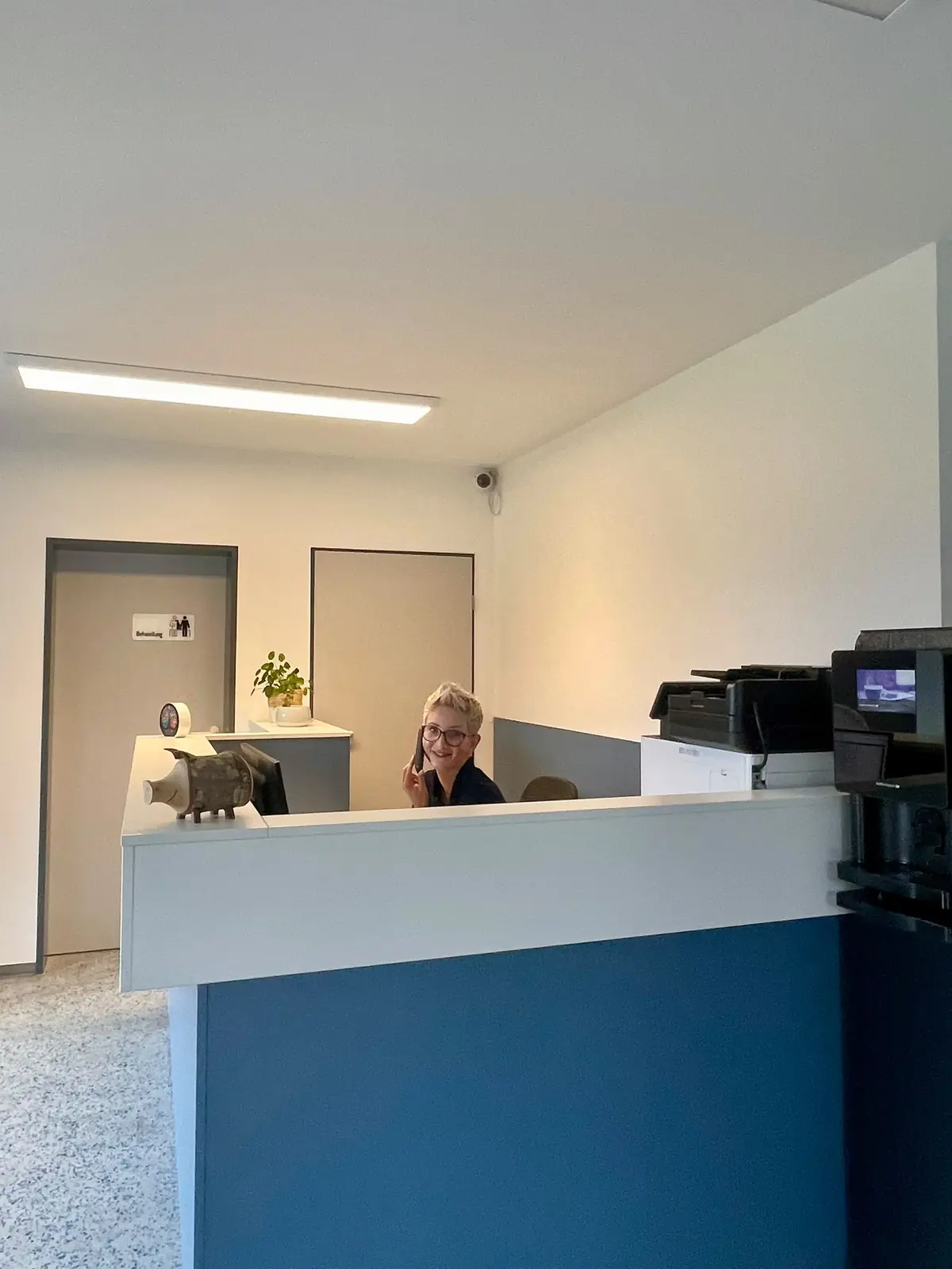 Empfangstheke mit Mitarbeiterin am Arbeitsplatz